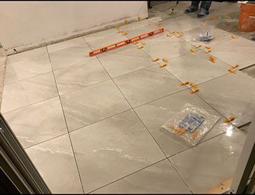 Large-format floor tile being laid with spacers and layout lines