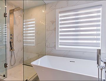 Freestanding tub beside a glass shower enclosure with shower panel and handheld