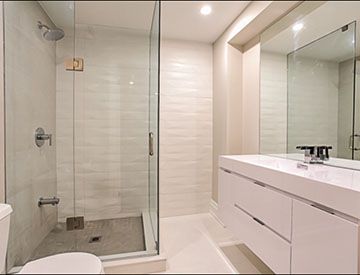 Frameless glass shower alongside a white floating vanity